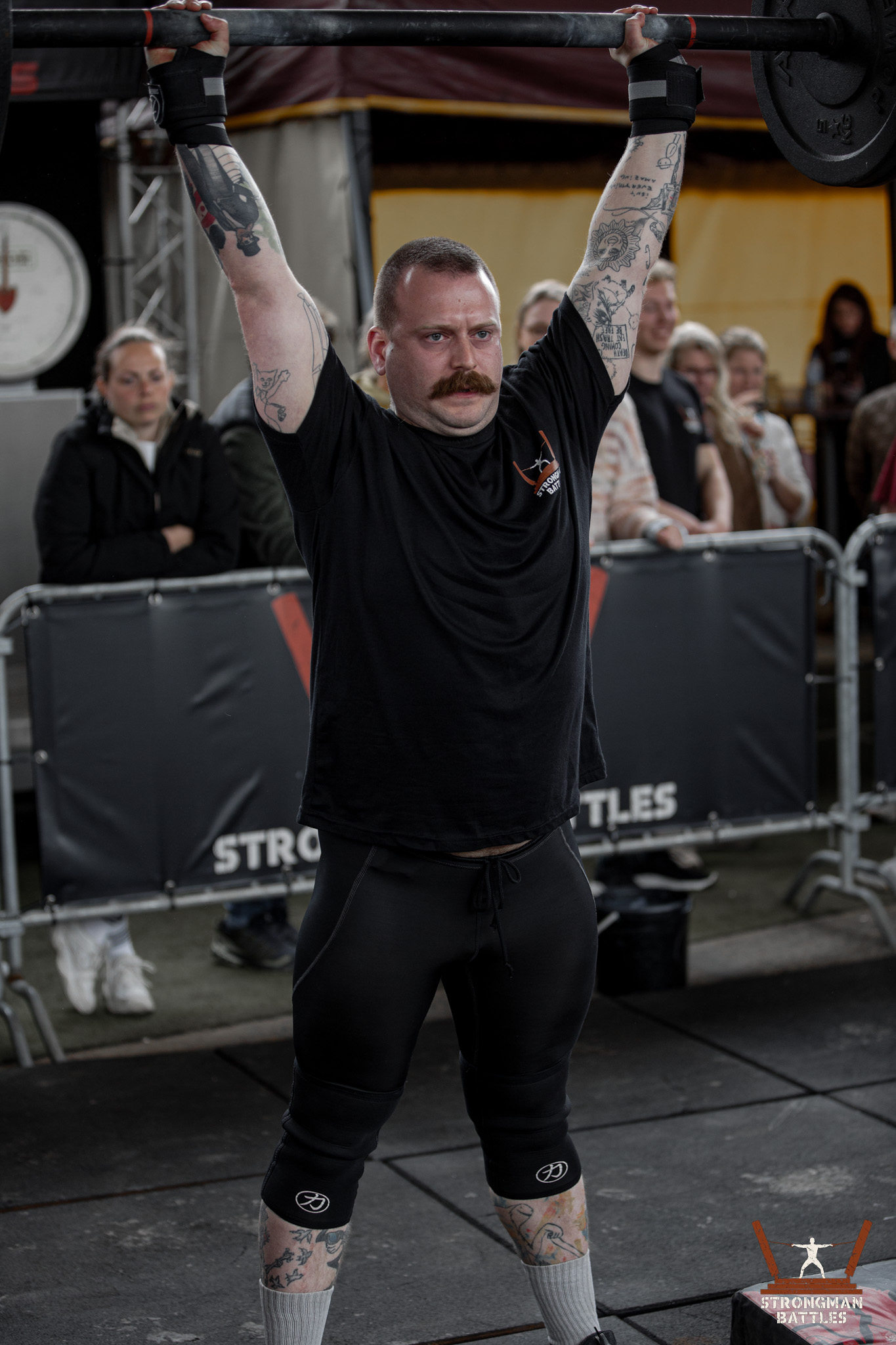 Participant holding an axle overhead at Strongman Battles